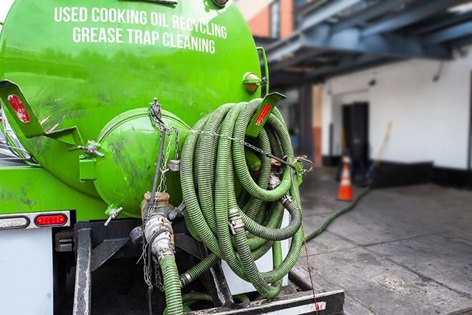 a technician pumping a grease trap in a commercial building in Goldenrod